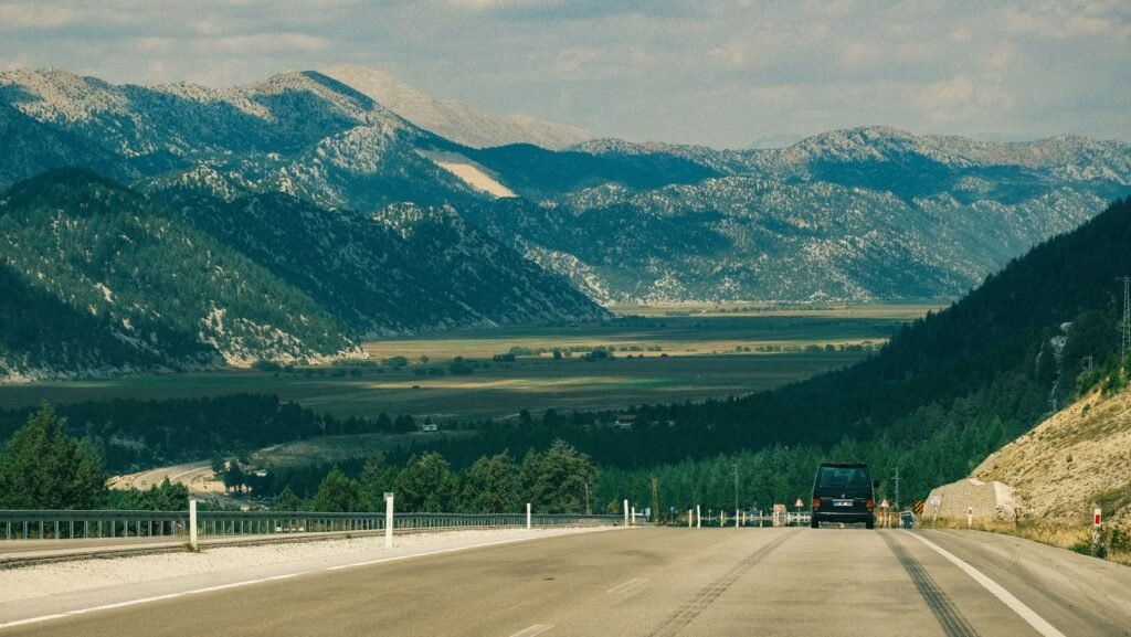Car driving down a highway with mountains in the background