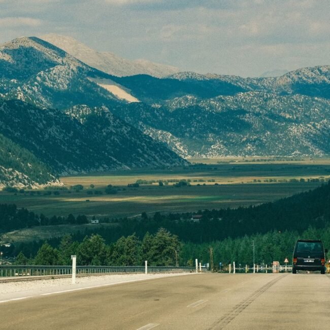 Car driving down a highway with mountains in the background