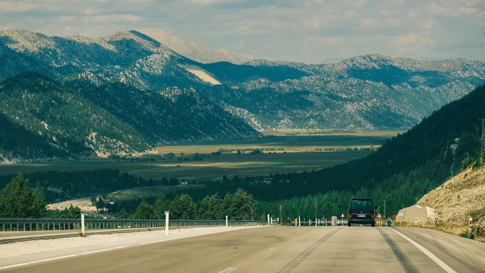 Car driving down a highway with mountains in the background