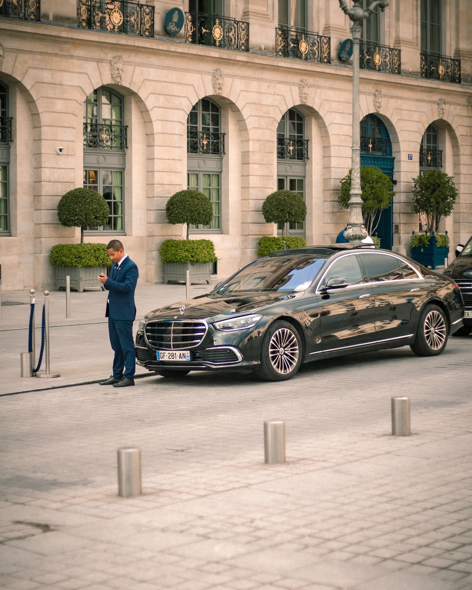 Chauffeur in a dark suit standing beside a black luxury car