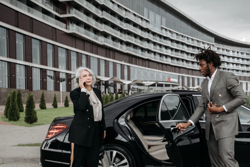 Chauffeur in a grey suit opening a car door for a passenger