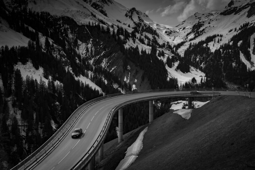 Grey car driving on a road near a snow covered mountain