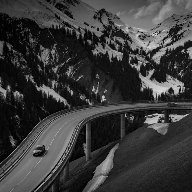 Grey car driving on a road near a snow covered mountain